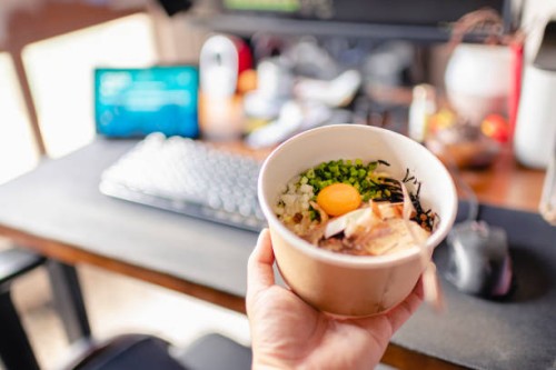 first person view with a paper bowl of ramen with egg york and char siu in front of desktop pc - junk food stock pictures, royalty-free photos & images