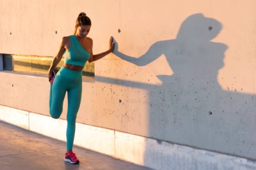 fit woman stretching legs near wall - fashion stock pictures, royalty-free photos & images