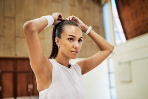 fit young woman tying her hair while getting ready for exercising and training in a sport center or gym. one determined and dedicated athlete looking focused and prepared for a workout or competition - hairstyle stock picture