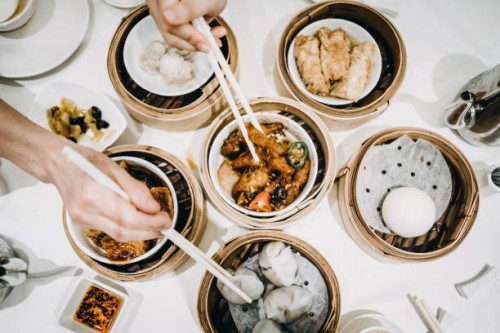 flat lay chinese dim sum time, various traditional dim sum freshly served on table and human hands picking up with chopsticks - junk food stockfoto's en -beelden