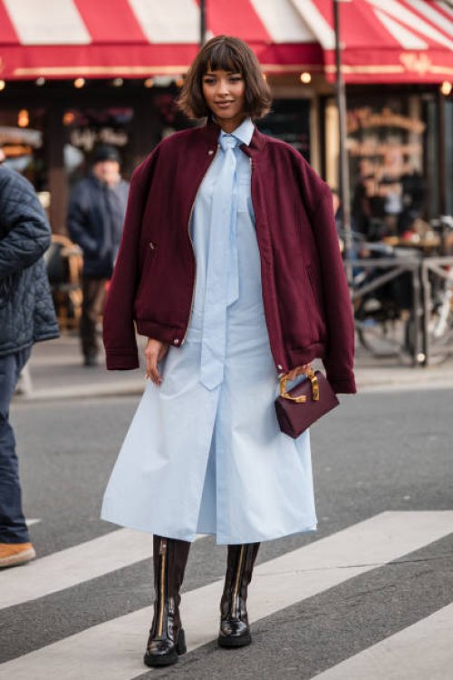 Flora Coquerel wears light blue shirt dress with matching tie, burgundy jacket, black lace tights, brown boots, burgundy bag, outside Casablanca,...