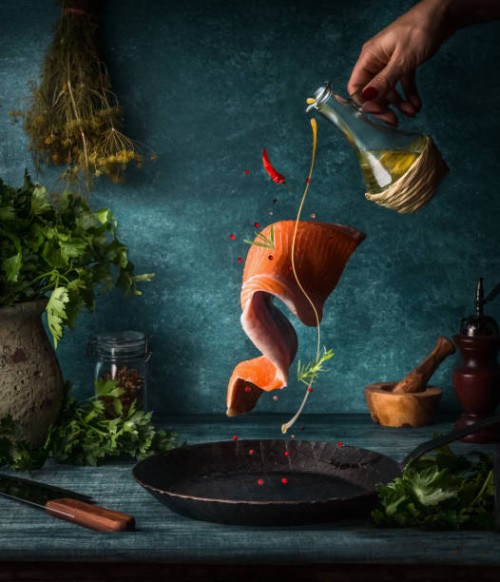 flying salmon fillet with herbs, spices and female hand with pouring olives oil - food stock pictures, royalty-free photos & images