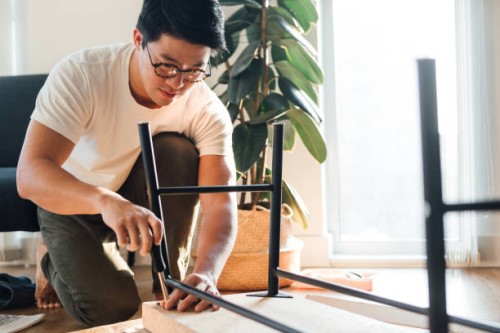 focused young man assembling furniture at home - home decoration stock pictures, royalty-free photos & images