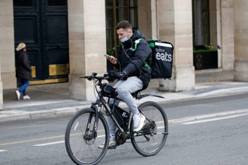 Food deliverer for Uber Eats checks his GPS as he rides his bicycle during the coronavirus outbreak on February 17 in Paris, France. With the closure...