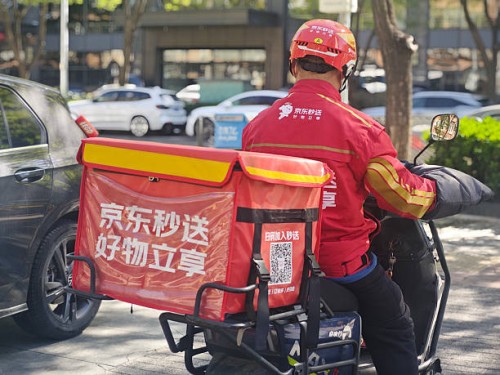 Food delivery rider of JD Takeaway, the food delivery service under China's e-commerce giant JD.com, rides an electric bicycle along a road on April...