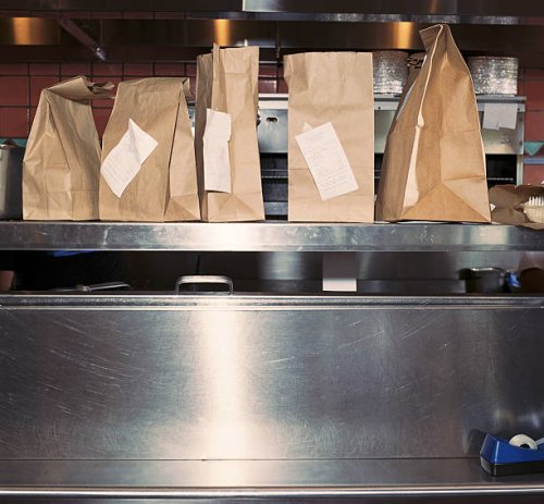 food in take out bags with receipts, sitting on restaurant shelf - junk food stock pictures, royalty-free photos & images