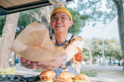 food truck owner picks up the burger - junk food stock pictures, royalty-free photos & images