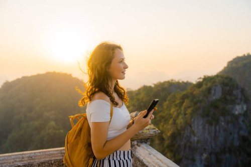 frau mit smartphone auf dem gipfel des wat tham sua in krabi bei sonnenuntergang - travel stock-fotos und bilder