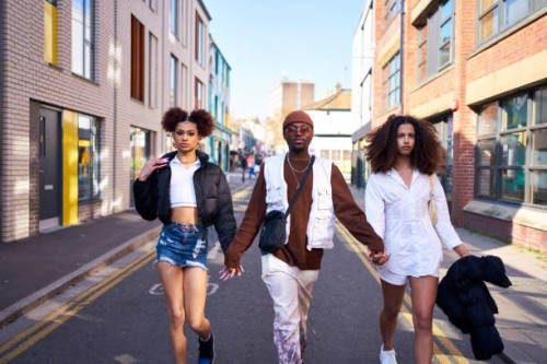 friends confidently walking along a city street in bright sunlight - fashion stock pictures, royalty-free photos & images