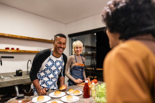 friends cooking and talking on hamburger night at home - junk food stock pictures, royalty-free photos & images