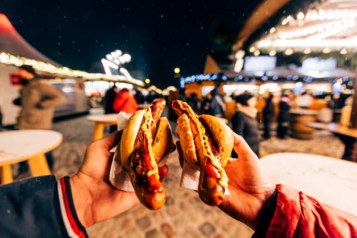 friends eating bratwurst sausage with mustard and ketchup at christmas market in berlin, germany - junk food stock pictures, royalty-free photos & images