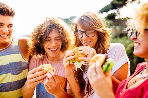 friends eating burgers - junk food stock pictures, royalty-free photos & images