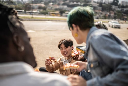 friends eating pizza in the park - junk food stock pictures, royalty-free photos & images