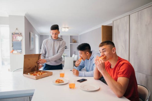 friends enjoying a take-away pizza - junk food stock pictures, royalty-free photos & images