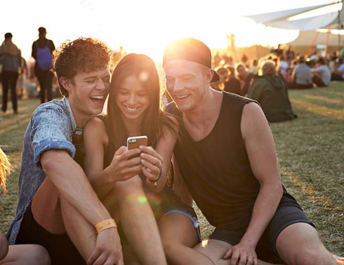 friends laughing, while looking at smartphone - concert stock-fotos und bilder