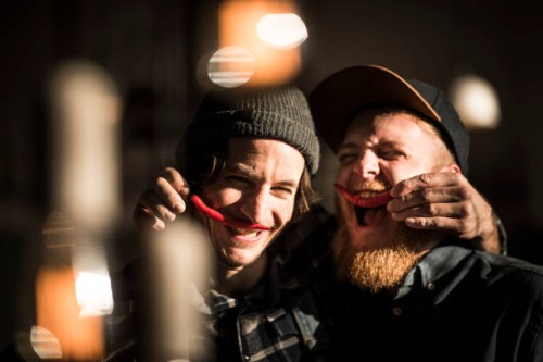 friends playing with chili peppers making moustaches - food stock pictures, royalty-free photos & images