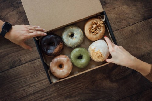 friends sharing a box of delicious crafted donuts - junk food stock pictures, royalty-free photos & images