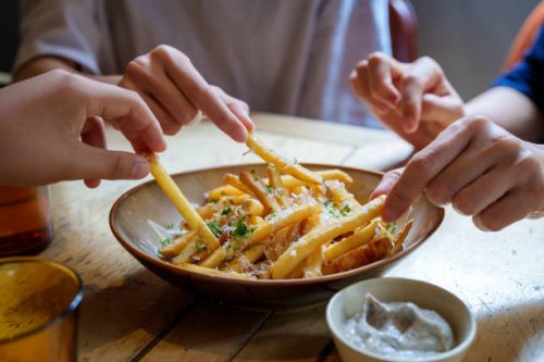 friends sharing and enjoying fries topped with parmesan cheese and truffled mayonnaise sauce. - food stock pictures, royalty-free photos & images