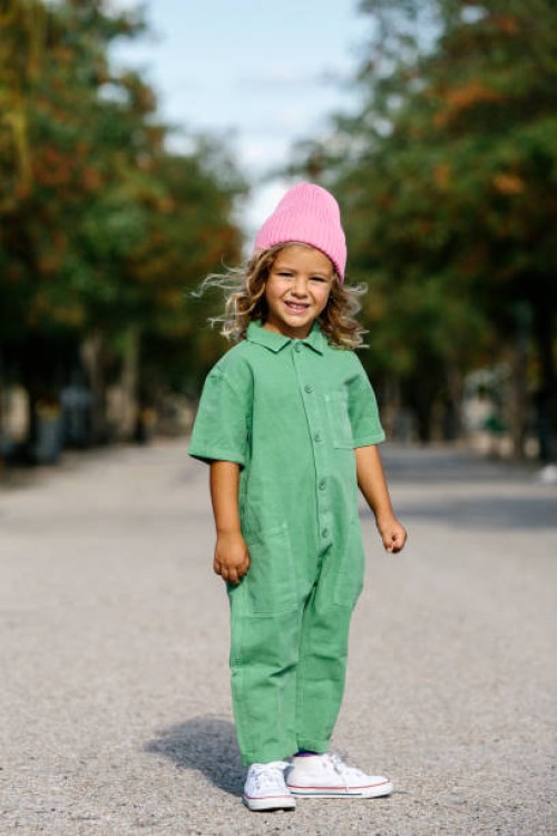 full-length portrait of a blonde, caucasian girl, wearing a woolen cap, smiling. with a park in the background. children, free time, vacations and leisure concept. - fashion stock pictures, royalty-free photos & images