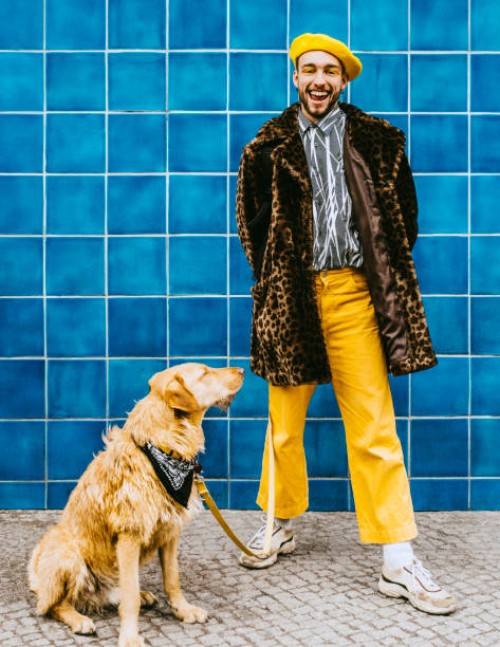 full length of happy young man with dog standing against blue tiled wall - fashion stock pictures, royalty-free photos & images