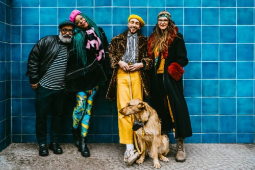 full length of smiling men and women with dog against blue wall - fashion stock pictures, royalty-free photos & images