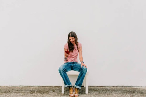 full length woman sitting using smartphone, studio shot on white background - fashion stock pictures, royalty-free photos & images