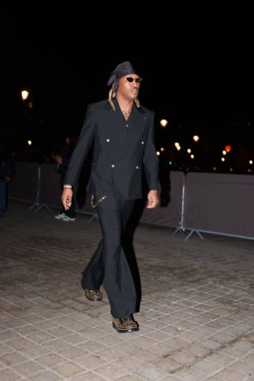 Future wears a scarf over the head, sunglasses, a black double breasted blazer jacket , flared pants, studded black leather shoes, before the Louis...