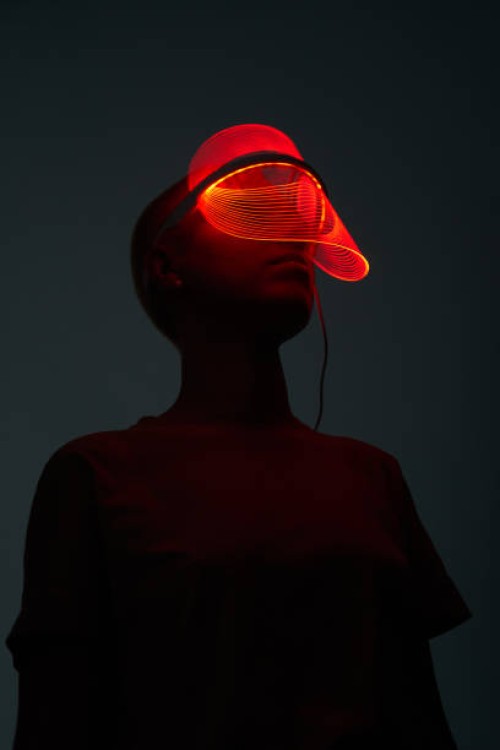 futuristic sot of young woman wearing led beauty mask with red lights over dark background - fashion stock pictures, royalty-free photos & images