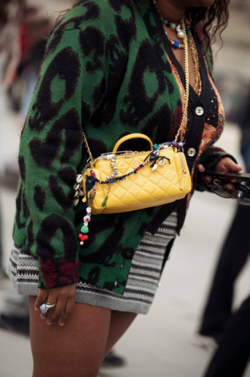 Gabriella Johnson wears grey sweater, yellow bag with bag charms and green and black striped dress outside the Chanel fashion show during the...