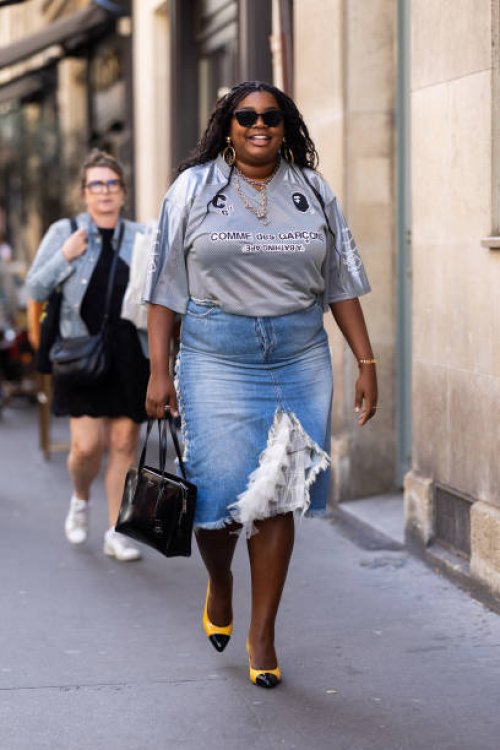 Gabriella Karefa-Johnson is seen wearing black sunglasses, a black leather Prada bag, black and yellow shiny pumps, pendant gold earrings, a chain...