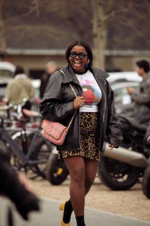 Gabriella Karefa-Johnson wears animal print mini skirt, white shirt with a print and black leather jacket and oran or pink Chanel bag outside Chanel...