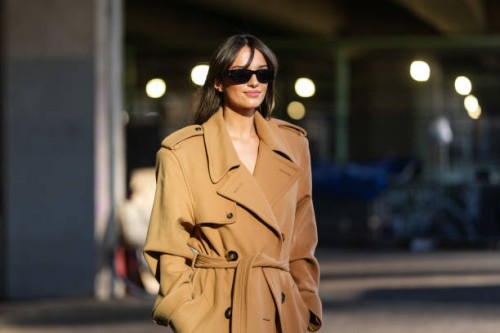 Gabrielle Caunesil wears black sunglasses, light brown double breasted belted trench coat, outside Stella McCartney, during the Paris Fashion week...