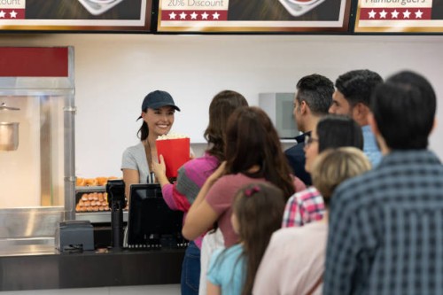 gelukkige vrouw die voedsel verkoopt bij de concessietribune bij de bioskoop - food stockfoto's en -beelden