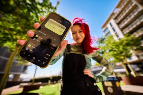 gen z adults outdoors with one person showing a smartphone displaying a bank balance and transactions. urban environment. low angle shot. - fashion stock pictures, royalty-free photos & images