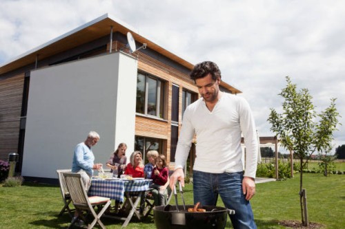 germany, bavaria, nuremberg, man cooking barbecue, family sitting in garden - garden decoration photos et images de collection