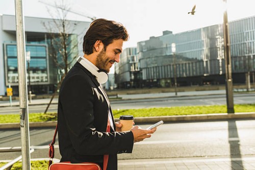germany, frankfurt, young businessman walking the city with cup of coffee, using mobile phone - junk food stock pictures, royalty-free photos & images