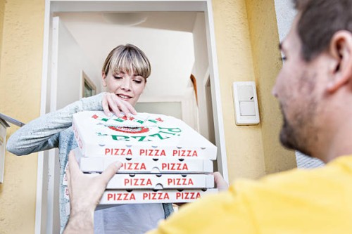 germany, north rhine westphalia, cologne, young woman taking pizza boxes from delivery man, smiling - junk food stock pictures, royalty-free photos & images