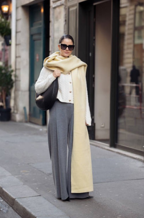 Gili Biegun wears grey pants, white knitted top with long sleeves, and pale yellow long wide scarf, balck leather bag and sunglasses during the...