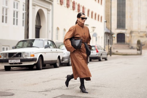 Gili Biegun wears, long brown leather coat, black bag, black long leather gloves, sunglasses and black shoes during the Copenhagen Fashion Week...