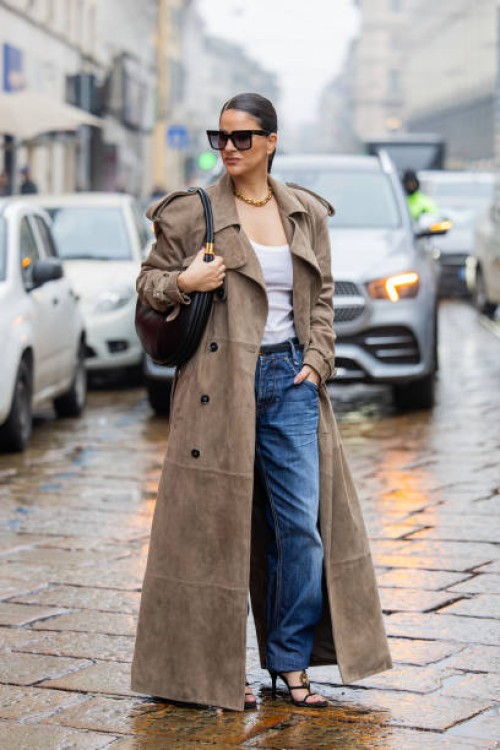 Gili Biegun wears long brown suede trench coat, denim jeans, black bag, creme white top and Gucci strappy sandals during the Milan Fashion Week...