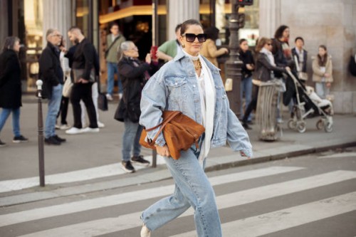 Gili Biegun wears white blouse, blue denim jacket, brown suede bag, sunglasses, golden necklace, blue jeans and white shoes outside the Vivienne...