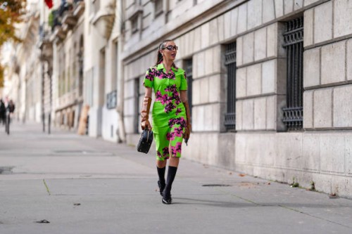 Ginevra Mavilla wears black sunglasses, gold earrings, bright green hot pink black floral pattern/detail short sleeve Miu Miu midi dress, shiny dark...