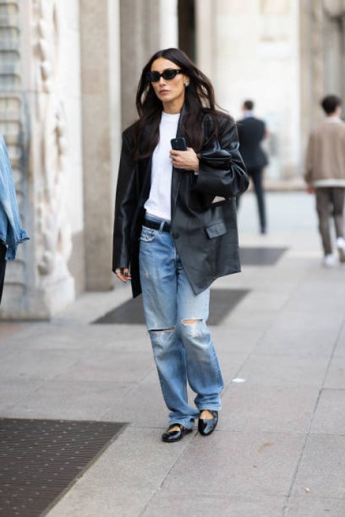 Giorgia Tordini wears black shiny leather ballerinas, silver hoop earrings, black sunglasses, a black belt, a black oversized leather jacket, a white...
