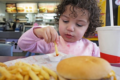 girl (2-3) sitting at table eating french fries, close-up - junk food stock pictures, royalty-free photos & images