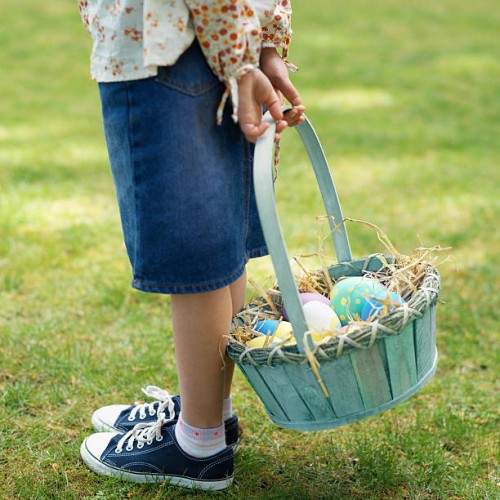 girl (6-7) with a basket of easter eggs - garden decoration stockfoto's en -beelden