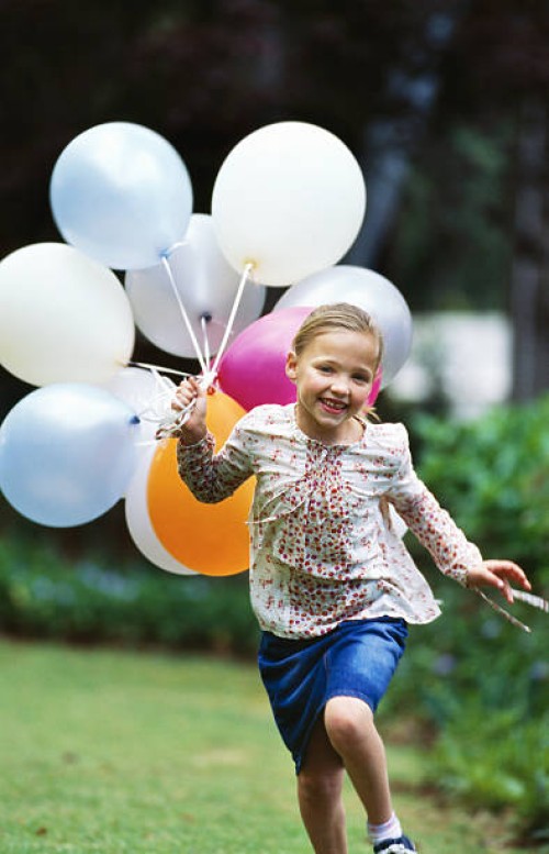 girl (8-9) running with a bunch of balloons - garden decoration stockfoto's en -beelden