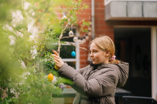 girl decorating a tree in the garden with colourful easter eggs - garden decoration stock pictures, royalty-free photos & images
