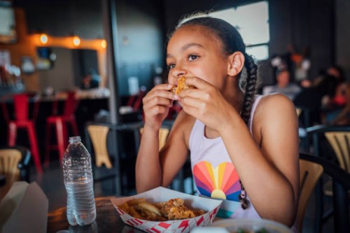 girl eating take out fried chicken with her fingers - junk food stock pictures, royalty-free photos & images