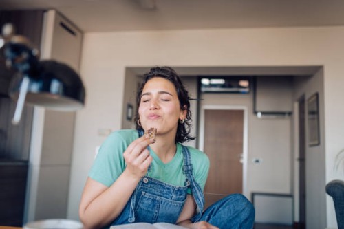 girl enjoying her favorite cookie at home - food stock pictures, royalty-free photos & images