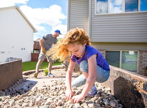 girl helping dad put landscaping rock in front of house - home decoration stock pictures, royalty-free photos & images